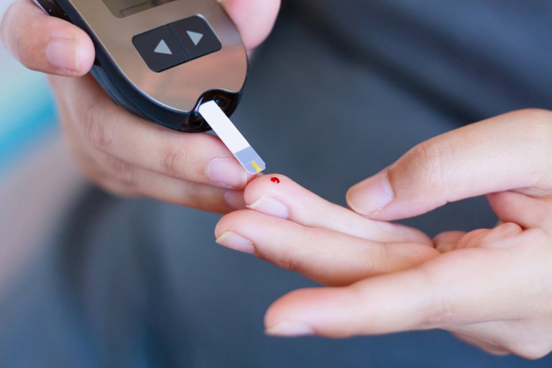 High-resolution close-up of blood glucose meter and finger prick for type 2 diabetes monitoring.